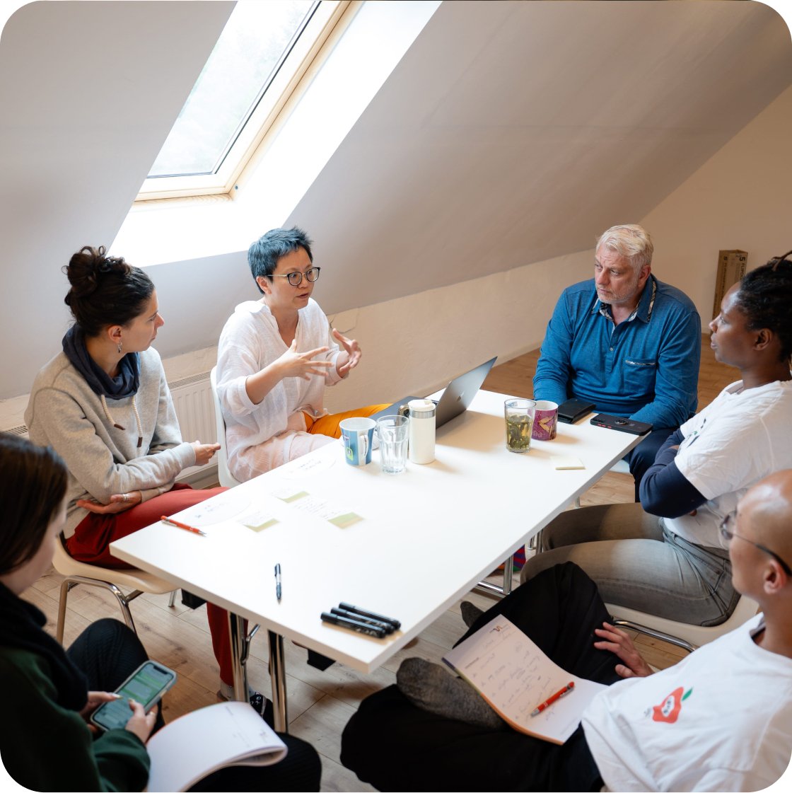 Teilnehmende eines UN LABs im gemeinsamen Gespräch an einem Tisch